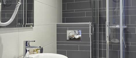Un baño moderno con un lavabo blanco, un inodoro y una ducha con mampara de vidrio.
