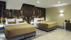 Ein Hotelzimmer mit zwei Betten, einem großen Wandbild, einem Schreibtisch und einem Stuhl.
