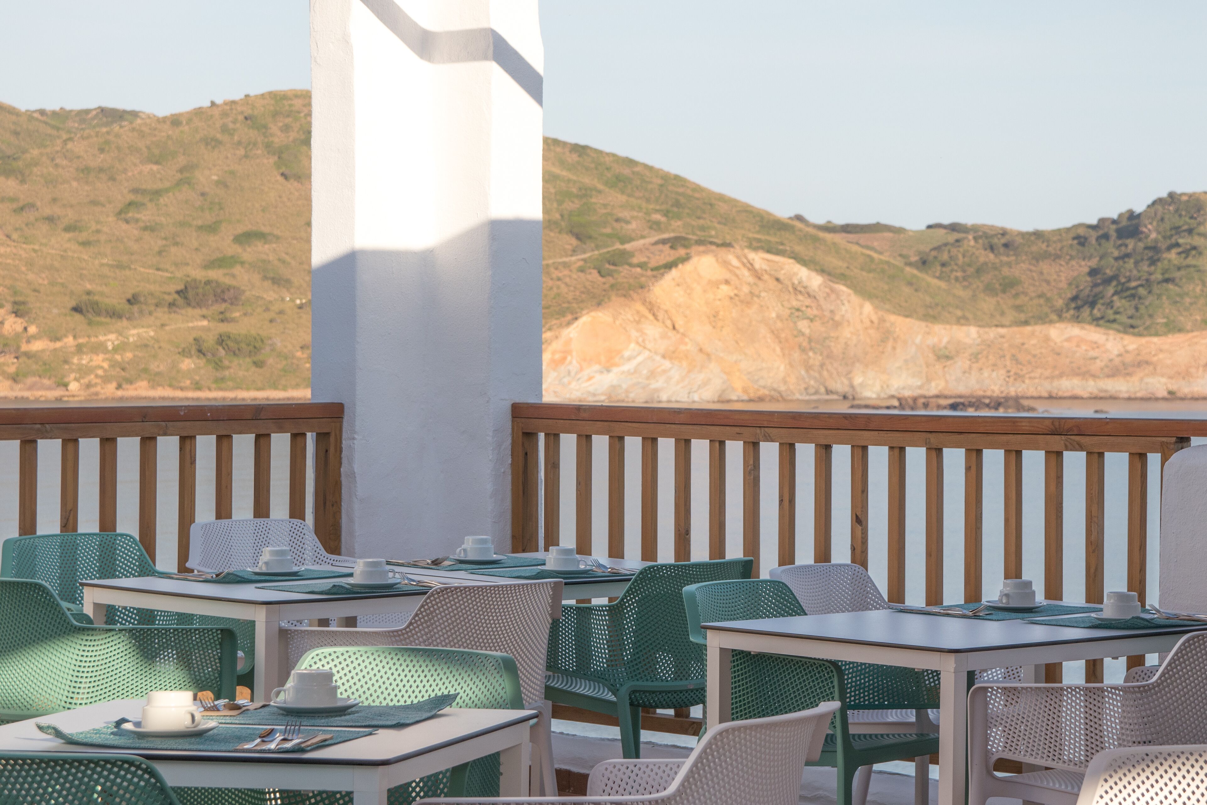 Une terrasse avec des sièges extérieurs, une vue sur une colline et une balustrade en bois.