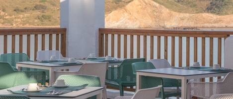 Une terrasse avec des sièges extérieurs, une vue sur une colline et une balustrade en bois.