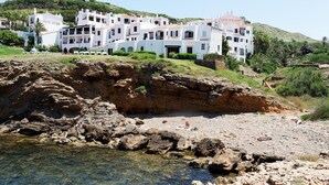 A coastal building with multiple balconies, situated on a rocky shoreline with clear water. - Comitas Tramontana Park (Mercadal)