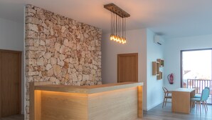 A modern reception area with a stone wall, wooden reception desk, and a dining area with chairs and a table. - Comitas Tramontana Park (Mercadal)