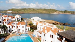 A coastal hotel with white buildings, a swimming pool, and a view of the sea and hills. - Comitas Tramontana Park (Mercadal)