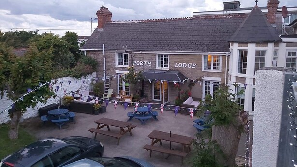 A building named 'Port Lodge' with a patio area featuring tables and chairs. - Porth Lodge Hotel (Newquay)