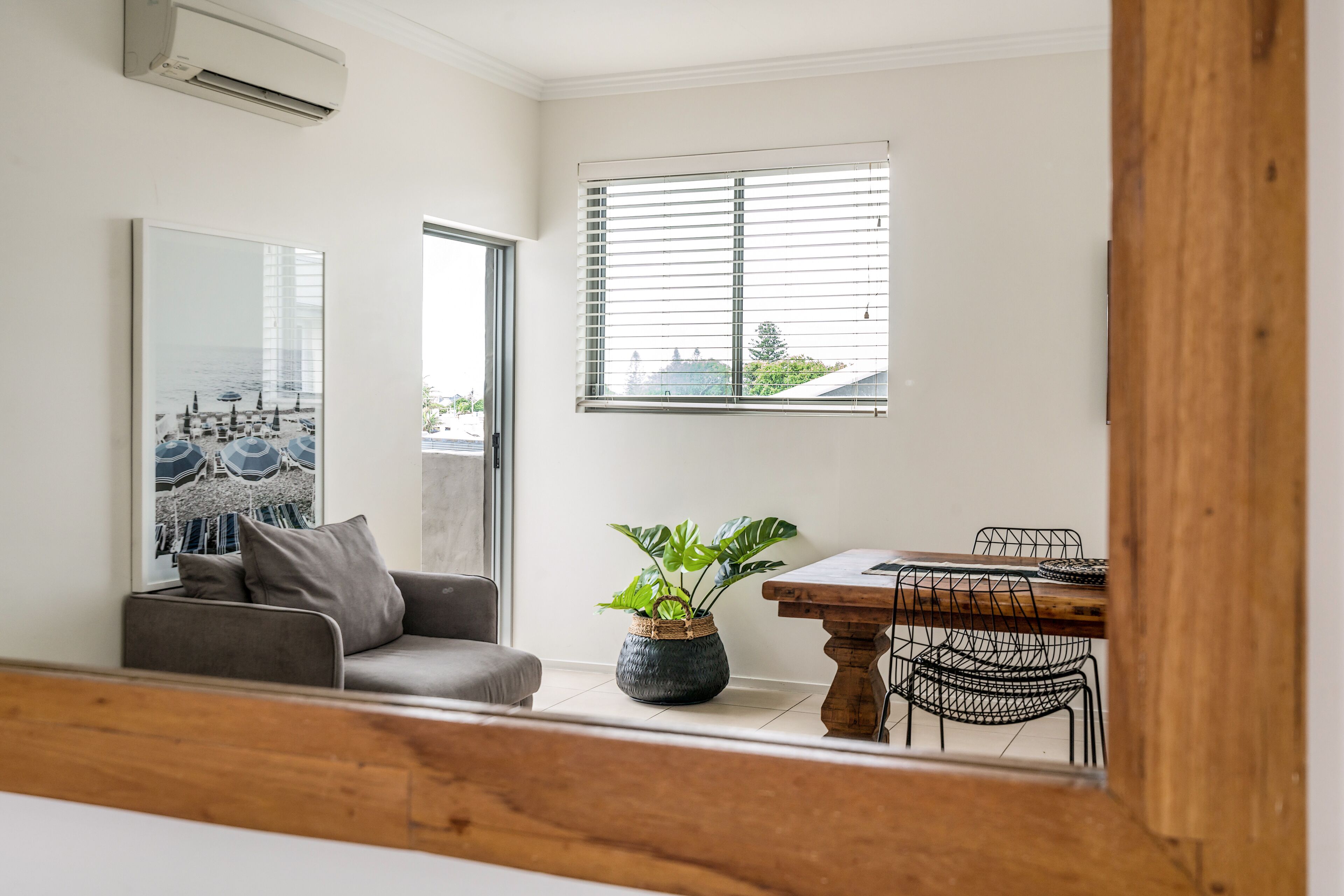 A modern living room with a grey sofa, a coffee table, and a potted plant.