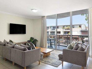 A modern living room with a sofa, a coffee table, and a TV mounted on the wall. - The Sebel Byron Bay (Byron Bay)