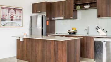 Una cocina moderna con armarios de madera, un refrigerador de acero inoxidable y un lavavajillas.