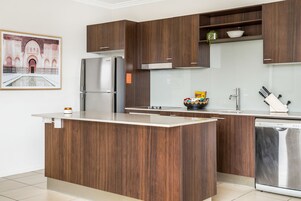 Una cocina moderna con armarios de madera, un refrigerador de acero inoxidable y un lavavajillas.