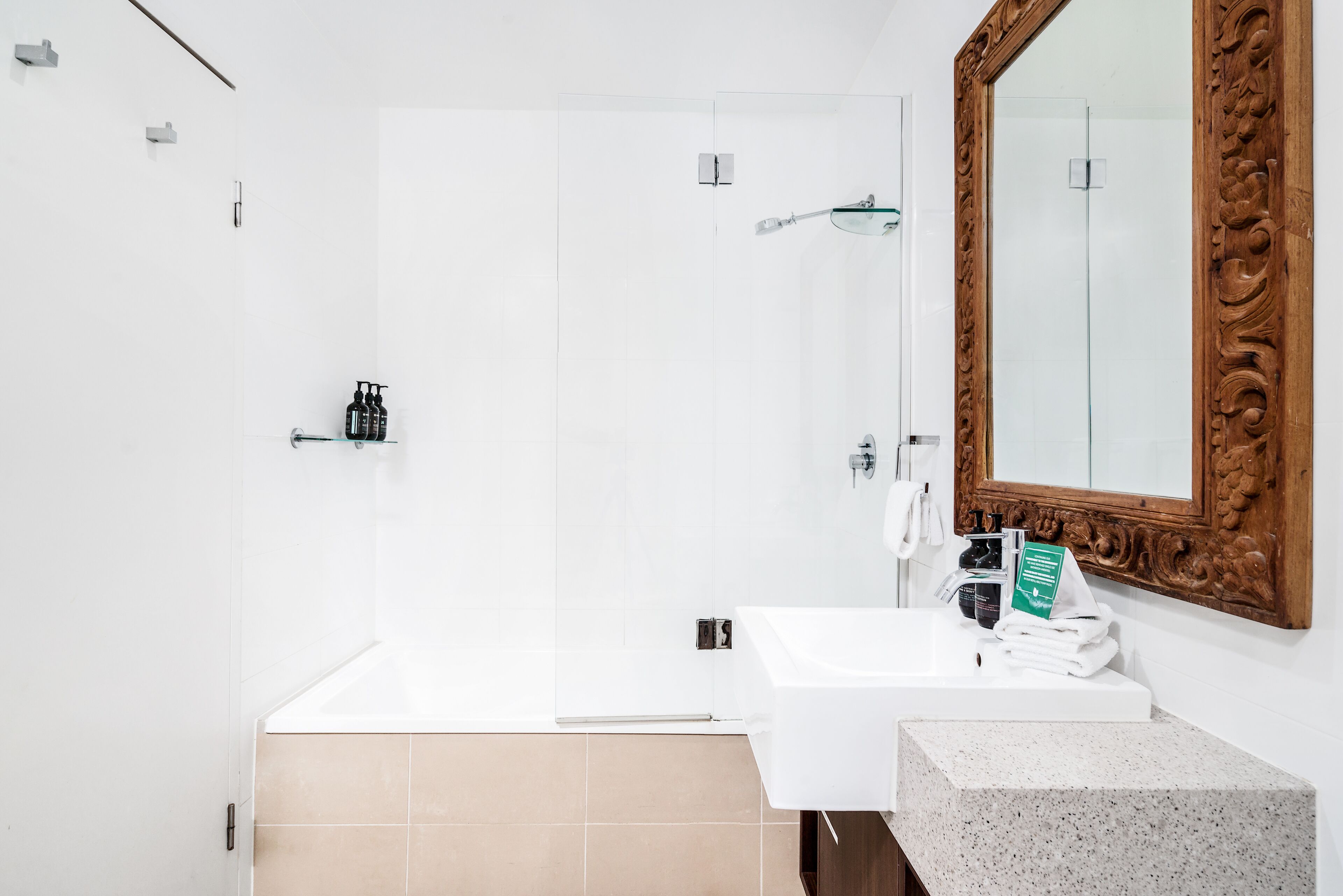 A modern bathroom with a white sink, a large mirror, and a shower area.