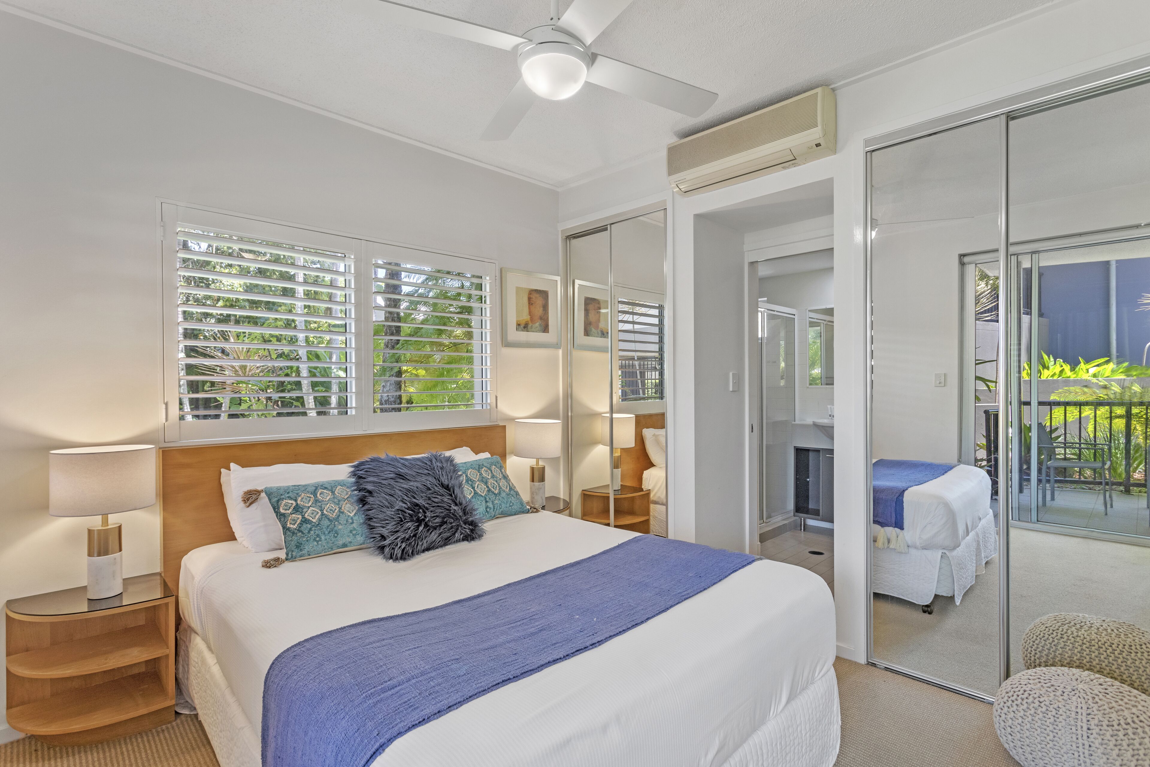 A modern bedroom with a large bed, a ceiling fan, and a sliding glass door leading to a balcony.