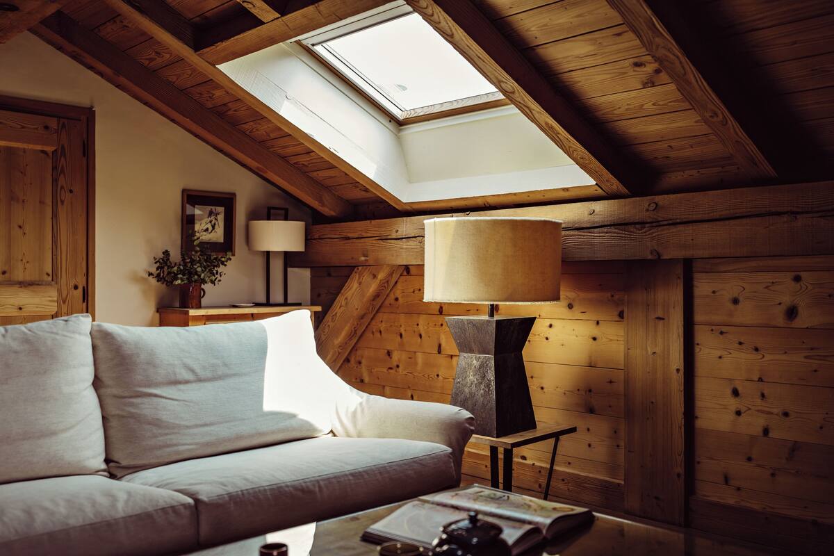 A cozy room with a sloped ceiling, a sofa, a lamp, and a framed picture on the wall.