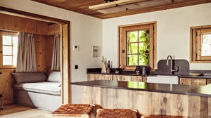 Une cuisine chaleureuse avec des meubles en bois, un îlot central doté de tabourets et une fenêtre donnant sur un paysage verdoyant.