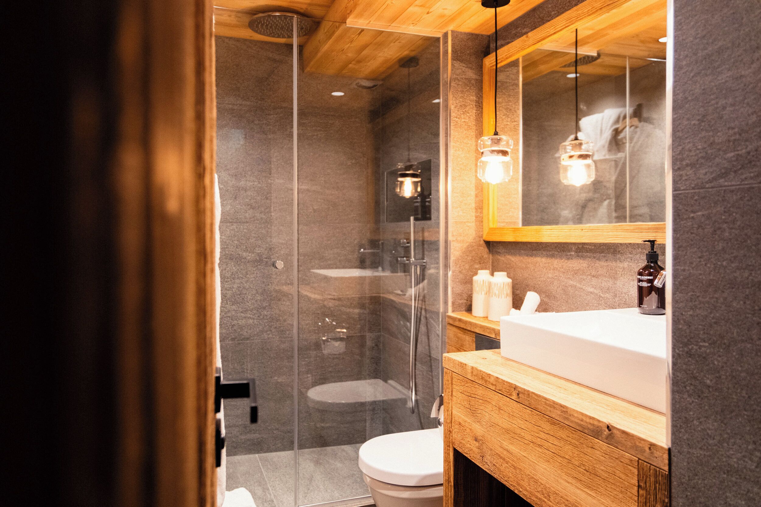 A modern bathroom with a glass-enclosed shower, a wooden vanity, and a large mirror.