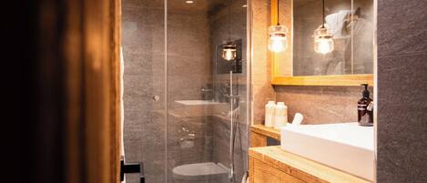 A modern bathroom with a glass-enclosed shower, a wooden vanity, and a large mirror.