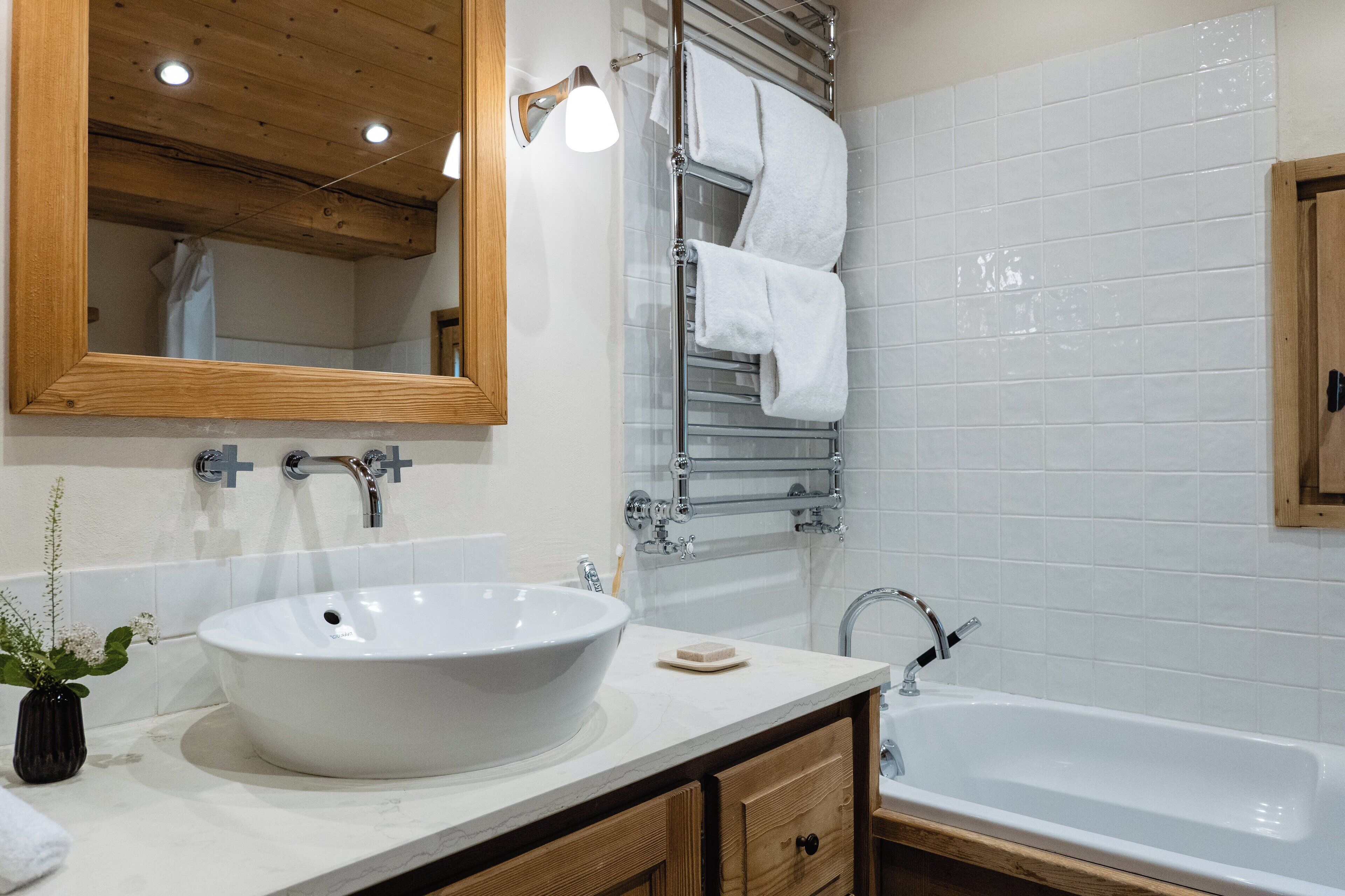 A modern bathroom with a large white sink, a mirror, and a glass shower enclosure.