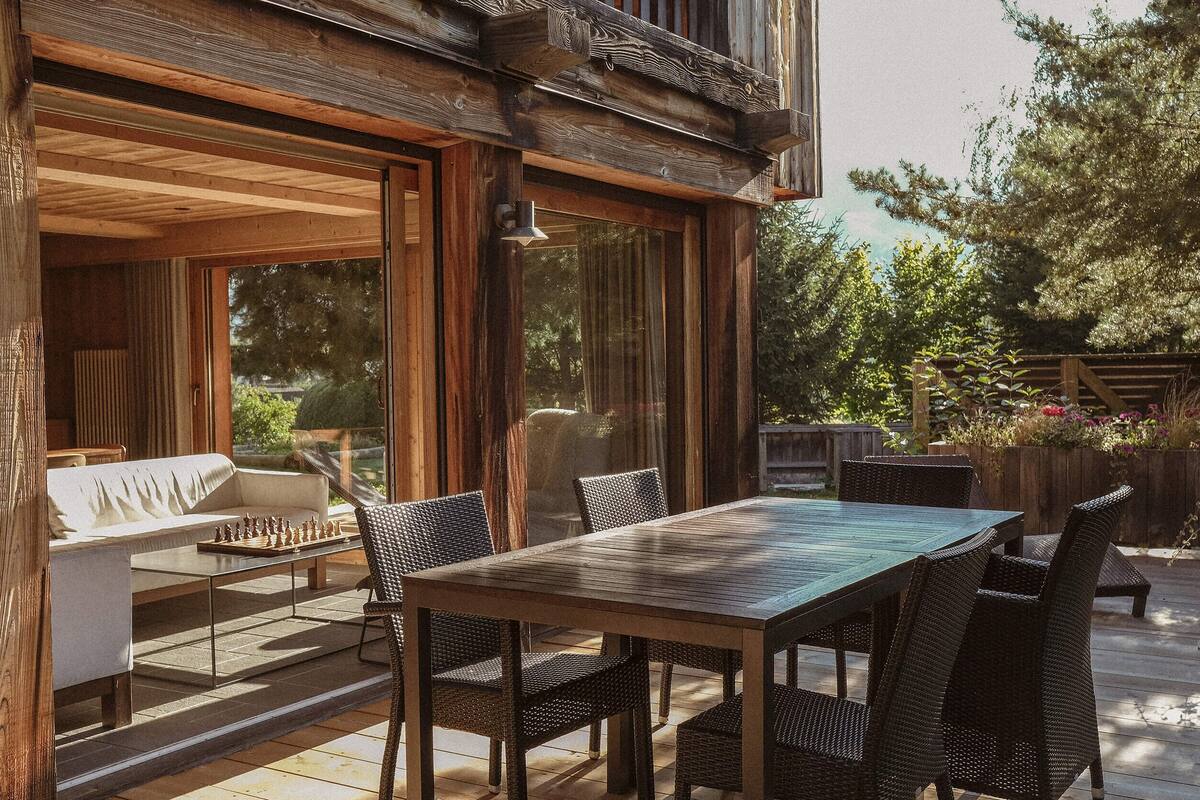 A wooden deck with a dining table and chairs, a sofa, and a chessboard.