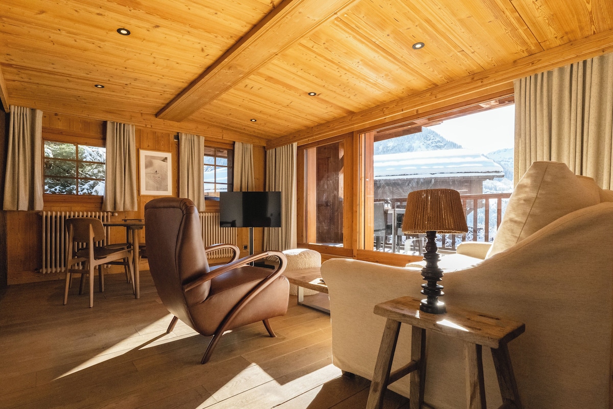 A wooden interior with a sofa, armchair, and dining table.