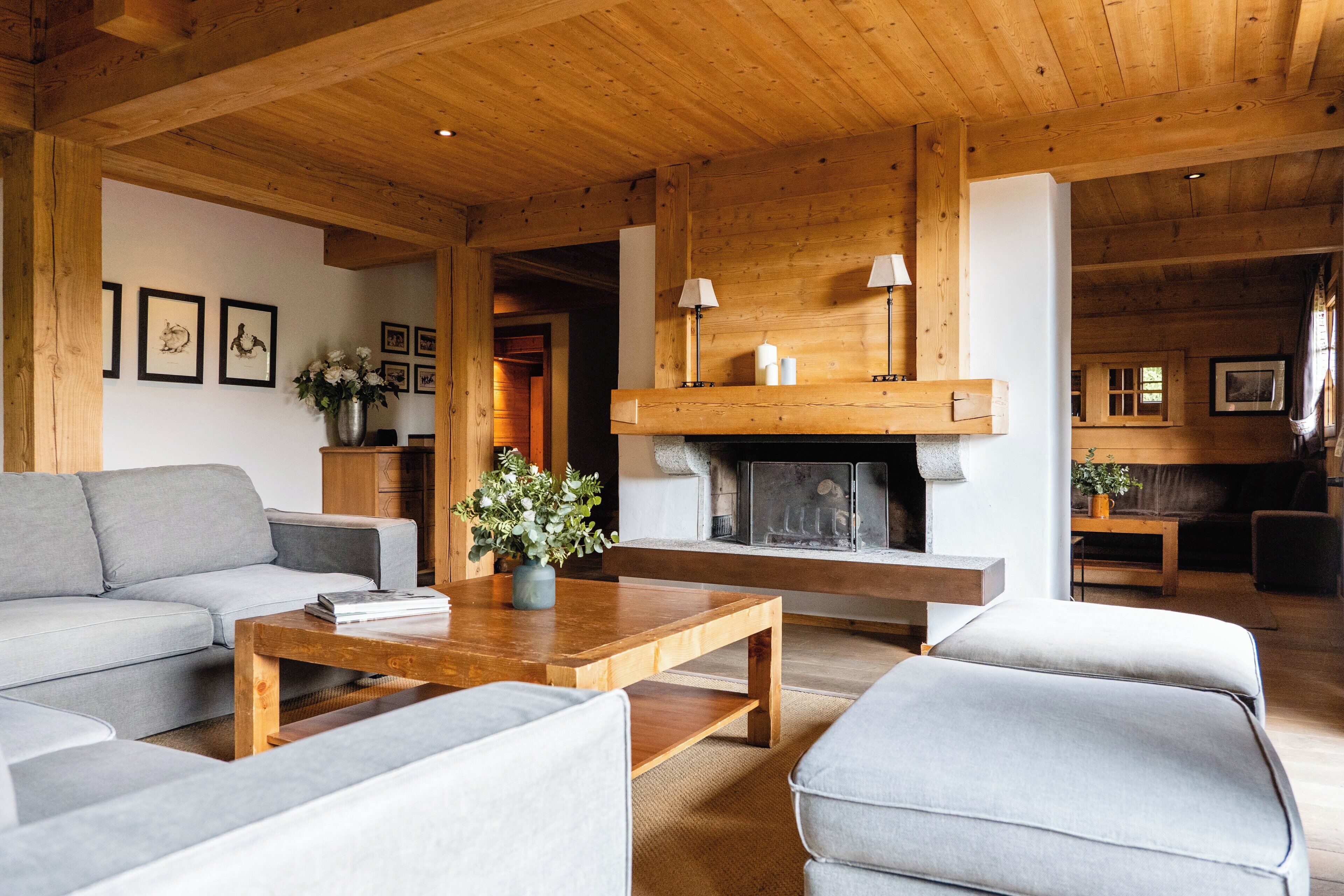 Un accogliente soggiorno con camino, soffitto in legno e divani grigi.