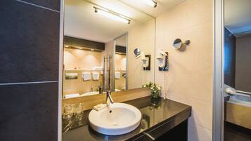 A modern bathroom with a large mirror, a sink, and a shower area.