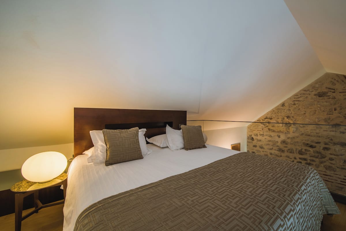 A bedroom with a large bed, a headboard, and a nightstand with a lamp.