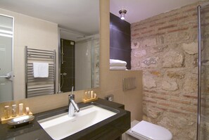 A bathroom with a modern sink, a glass shower enclosure, and a stone wall. - Hotel Vestibul Palace (Split)