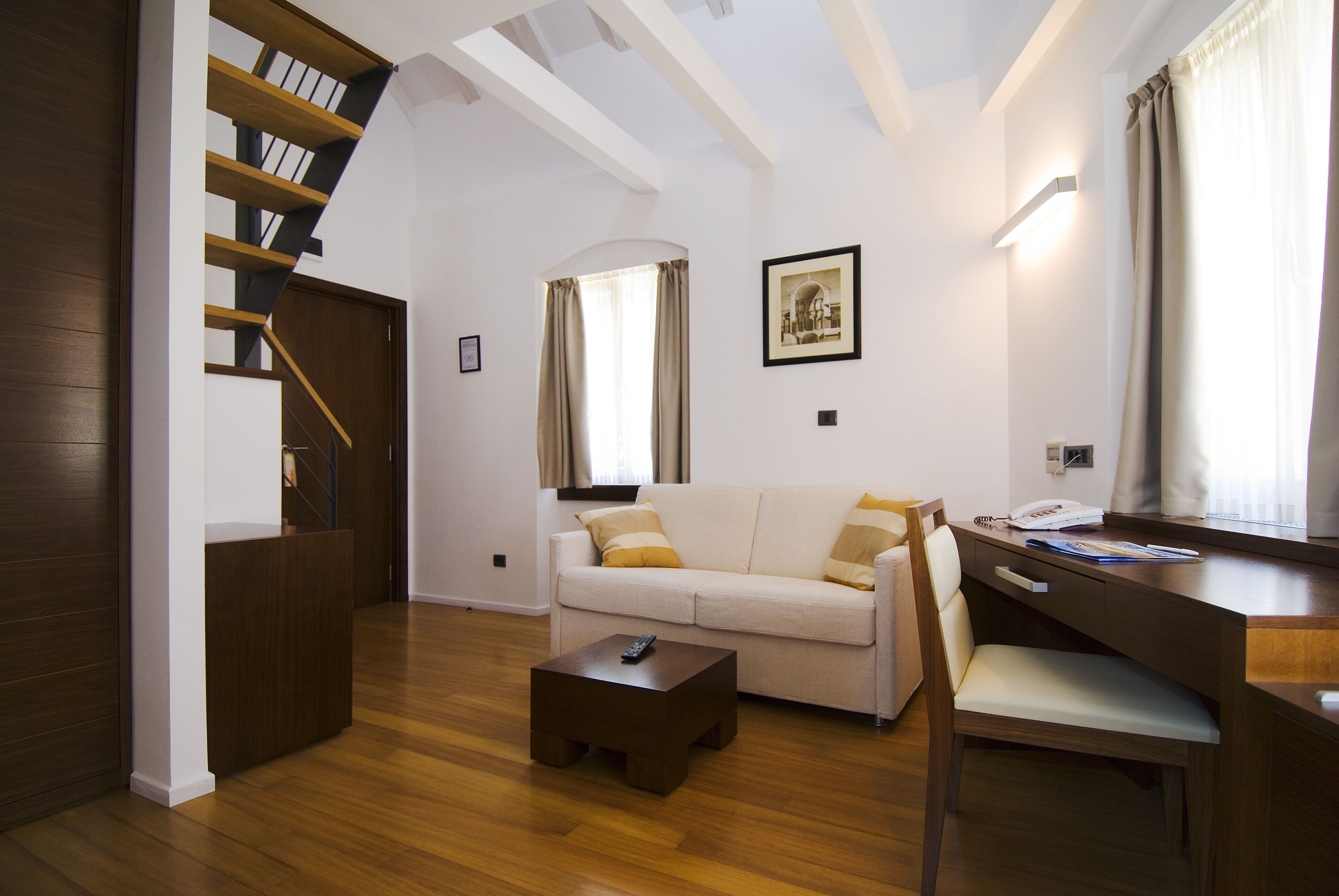 Una sala de estar moderna con una escalera, un sofá, una mesa de centro y un escritorio.