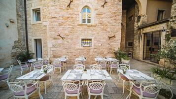 An outdoor dining area with stone walls, white tables, and chairs.
