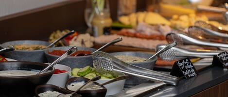 A buffet with various dishes and utensils, including a bowl of soup, a bowl of salad, and a bowl of dips.