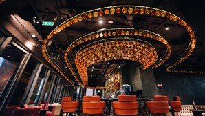 A bar area with circular ceiling decorations, seating, and a bar counter. - Radisson Blu Hotel, Cluj (Cluj-Napoca)