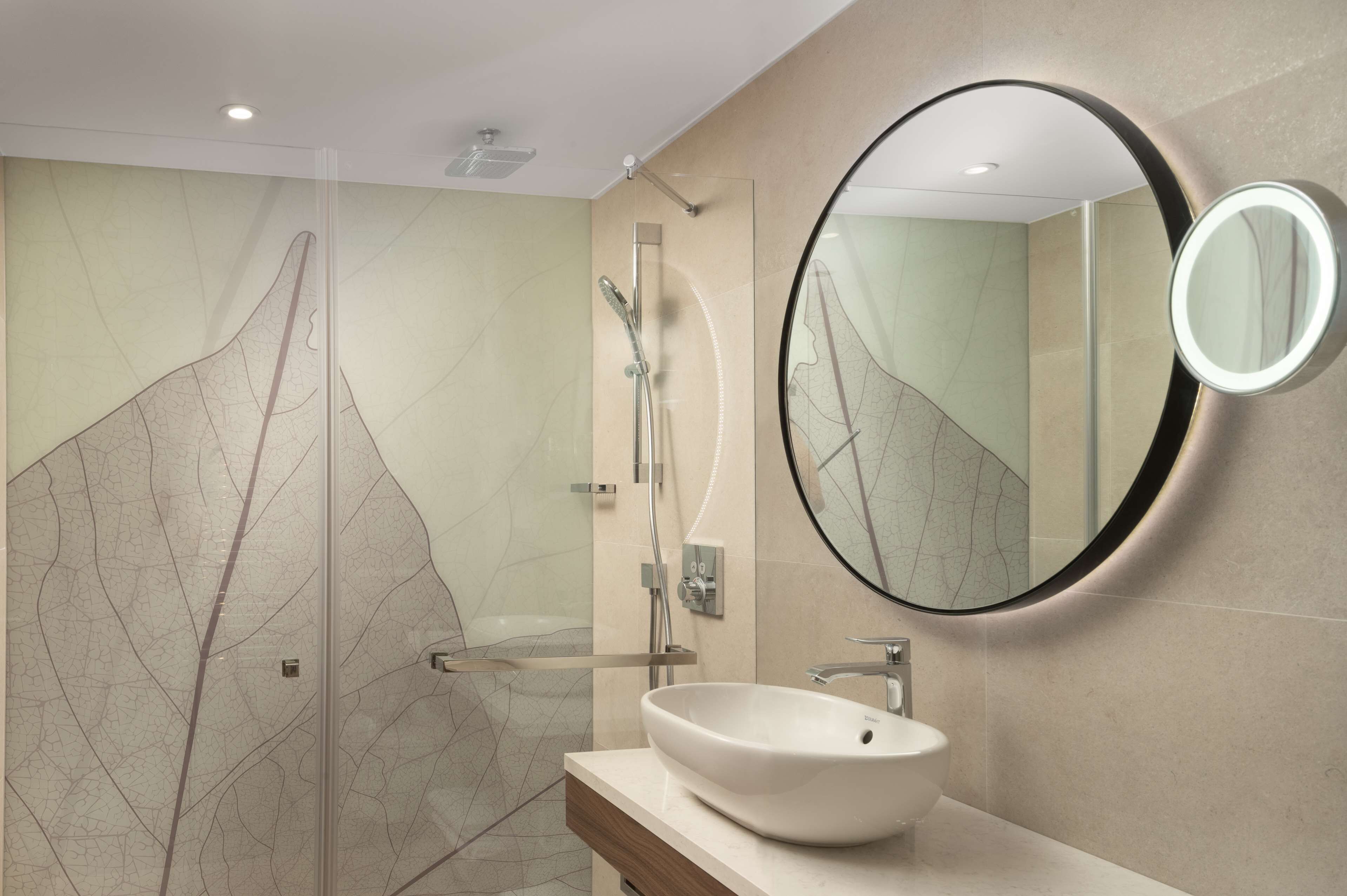 Une salle de bain moderne avec un grand miroir, un lavabo et un espace douche.