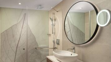 Une salle de bain moderne avec un grand miroir, un lavabo et un espace douche.