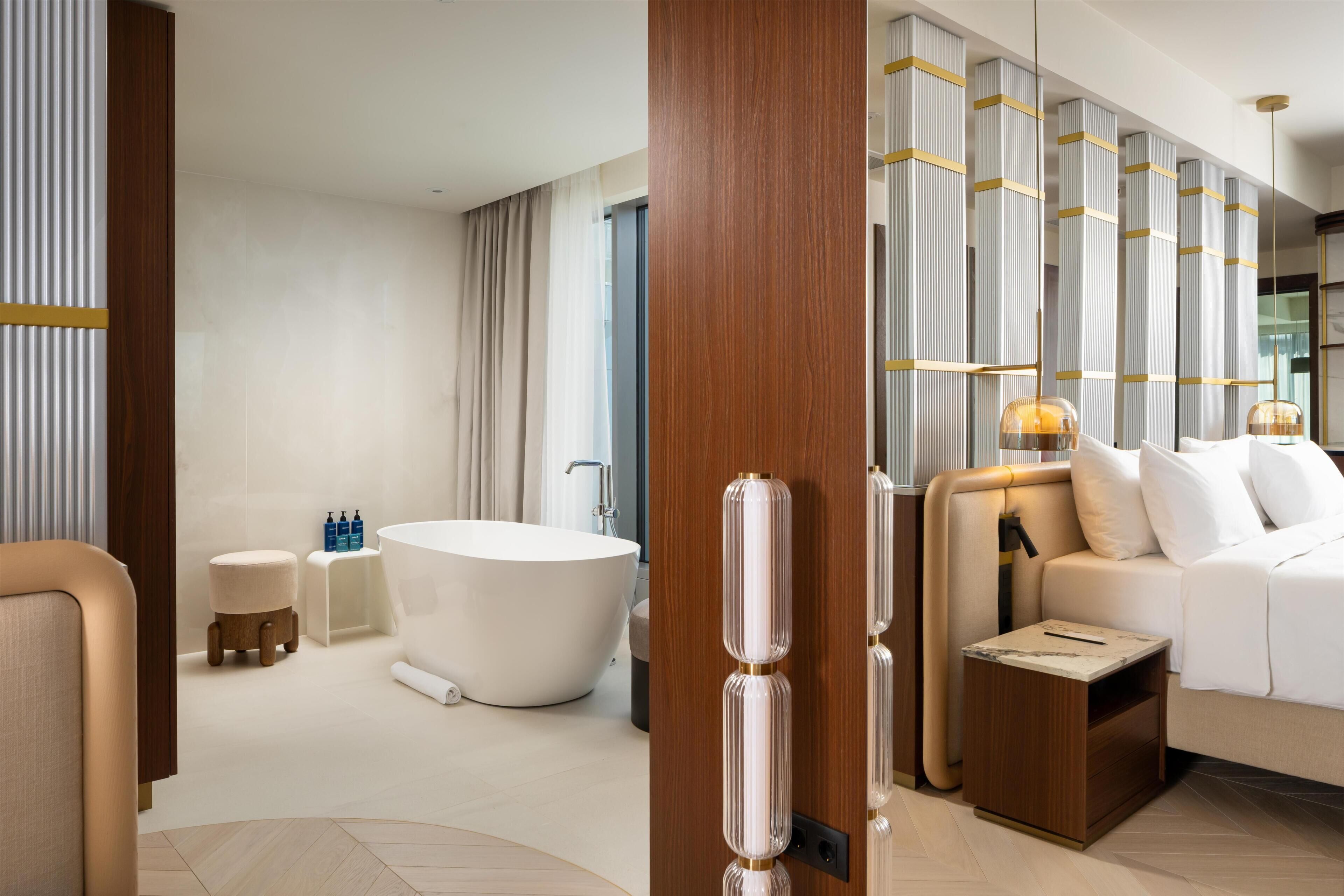A modern hotel bathroom with a freestanding bathtub, a vanity with a mirror, and a shower area.