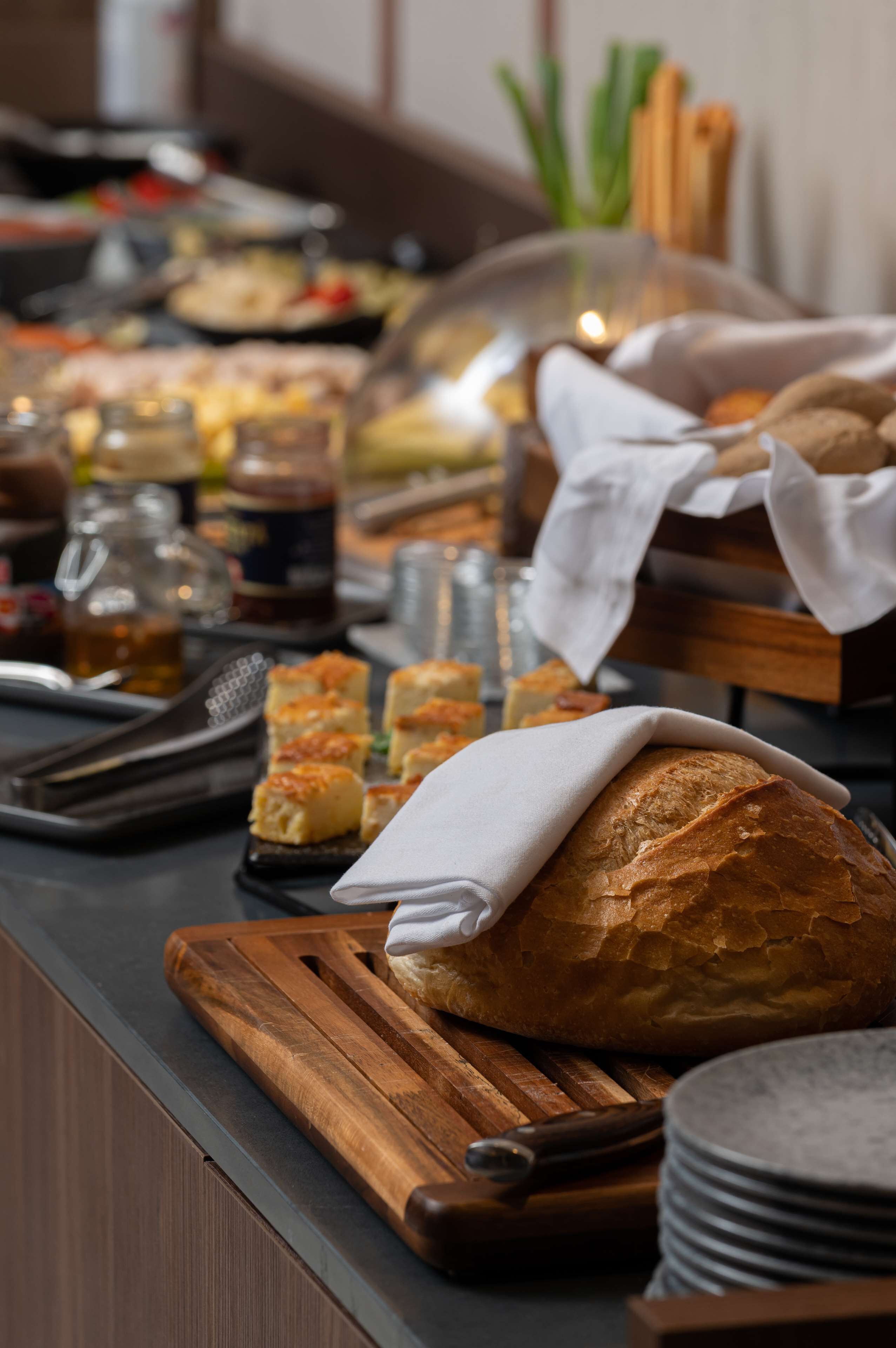 A buffet with various food items, including bread, pastries, and condiments.