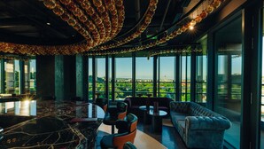 A modern interior with a marble bar, seating area, and large windows offering a city view. - Radisson Blu Hotel, Cluj (Cluj-Napoca)