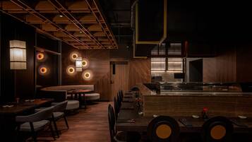 A modern restaurant interior with wooden paneling, round tables, and ambient lighting.