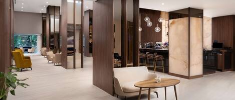 A modern hotel lobby with a seating area, a bar, and a large aquarium.
