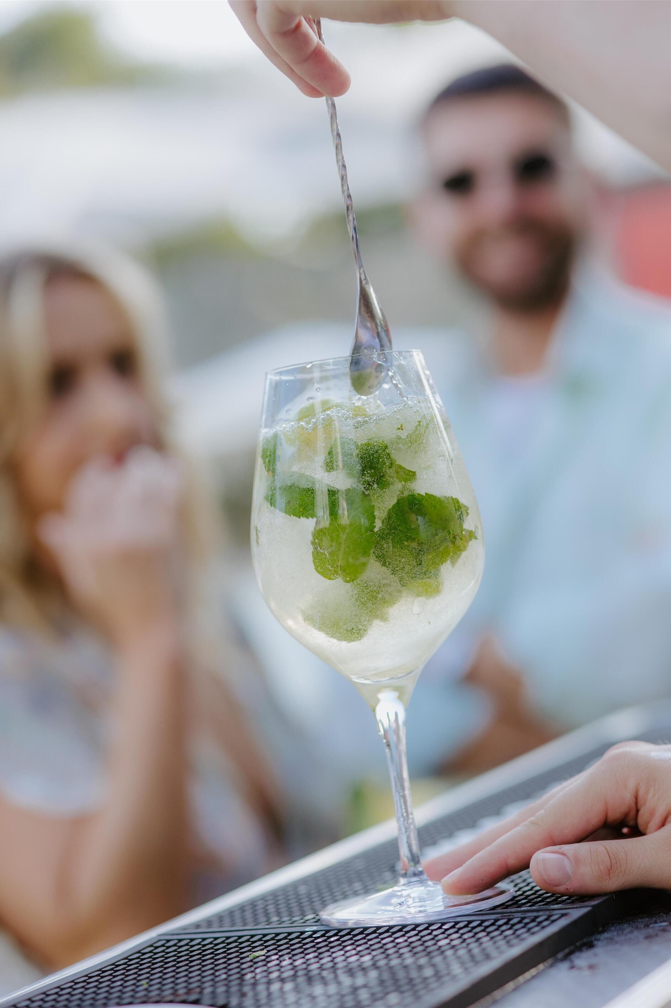 Un vaso de cóctel con hielo y hojas de menta sobre una barra.