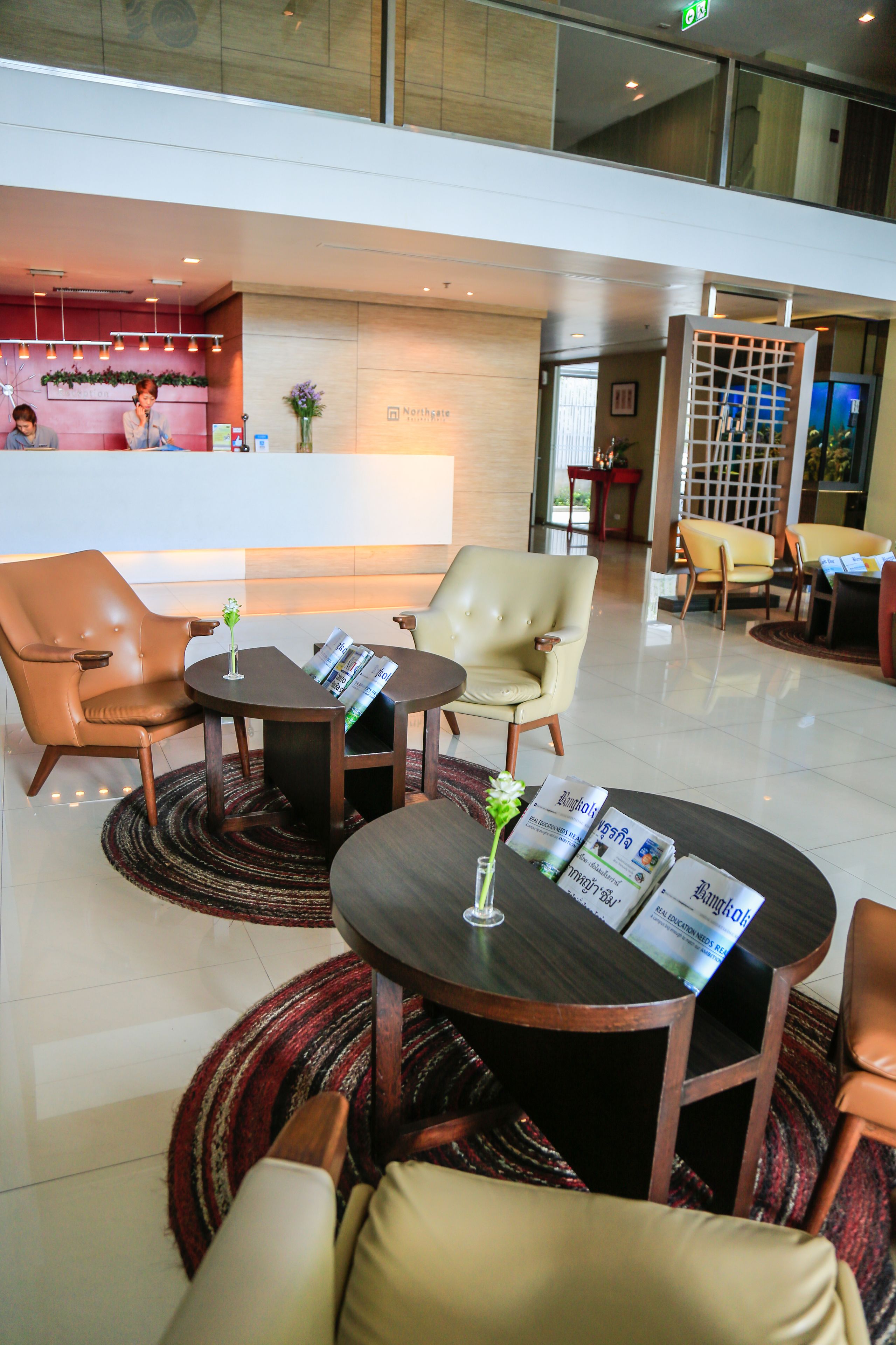 Eine Lobby mit Ledersesseln, einem Empfangstresen und einem Couchtisch mit Zeitschriften.