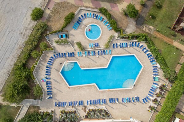 An aerial view of a swimming pool area with multiple sunbathing spots and a circular water feature. - Orfeu (Constanta)
