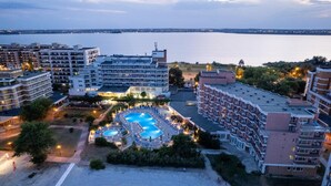 Um hotel com vários edifícios, piscina e vista para o mar.