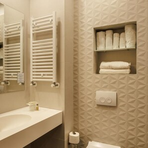 A bathroom with a white sink, towel rack, and a shelf with folded towels.