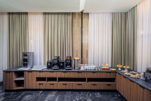 Habitación de hotel moderna con estación de café integrada, minibar y barra de desayuno.