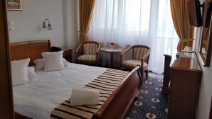 Una habitación de hotel con una cama grande, dos sillones, una mesita y un espejo.