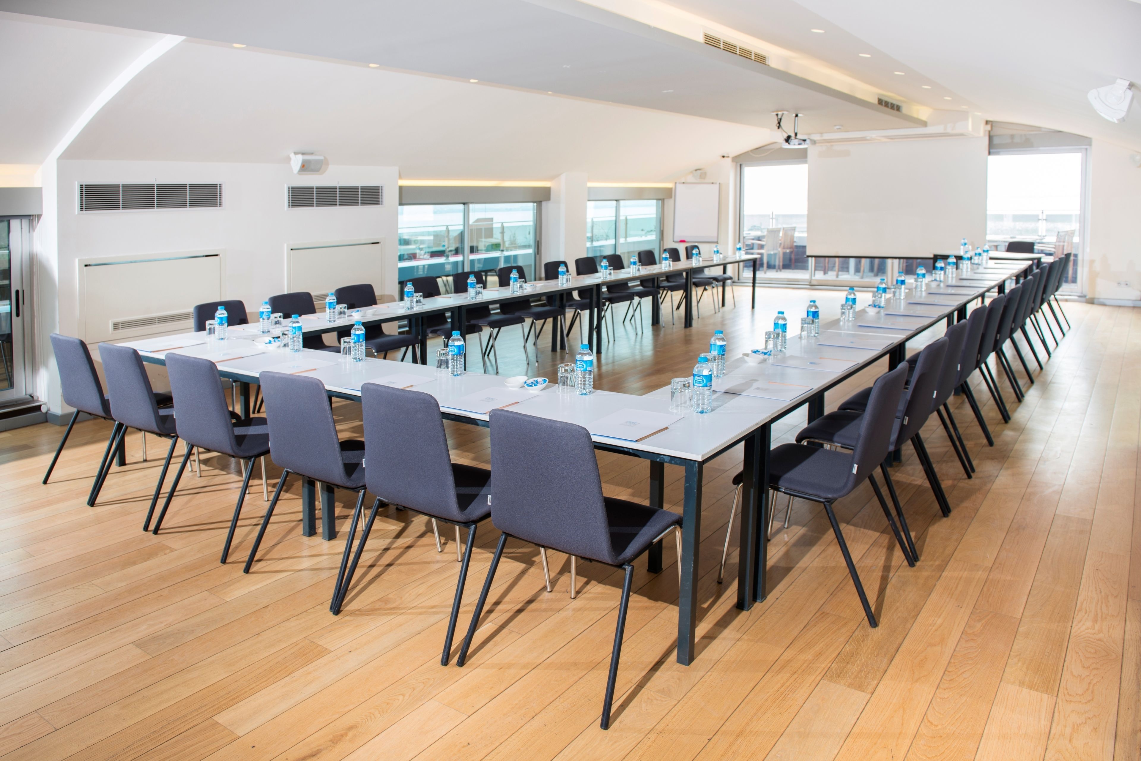 A conference room with a long table, chairs, and water bottles.