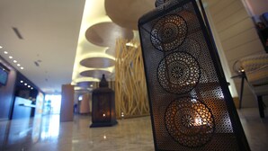 A corridor with a decorative metal railing, a wooden wall with vertical slats, and a reception desk in the background. - Wes Hotel Izmit (Izmit)