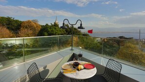 A dining table with plates, glasses, and cutlery on a balcony overlooking a scenic view with trees and a distant cityscape. - Wes Hotel Izmit (Izmit)