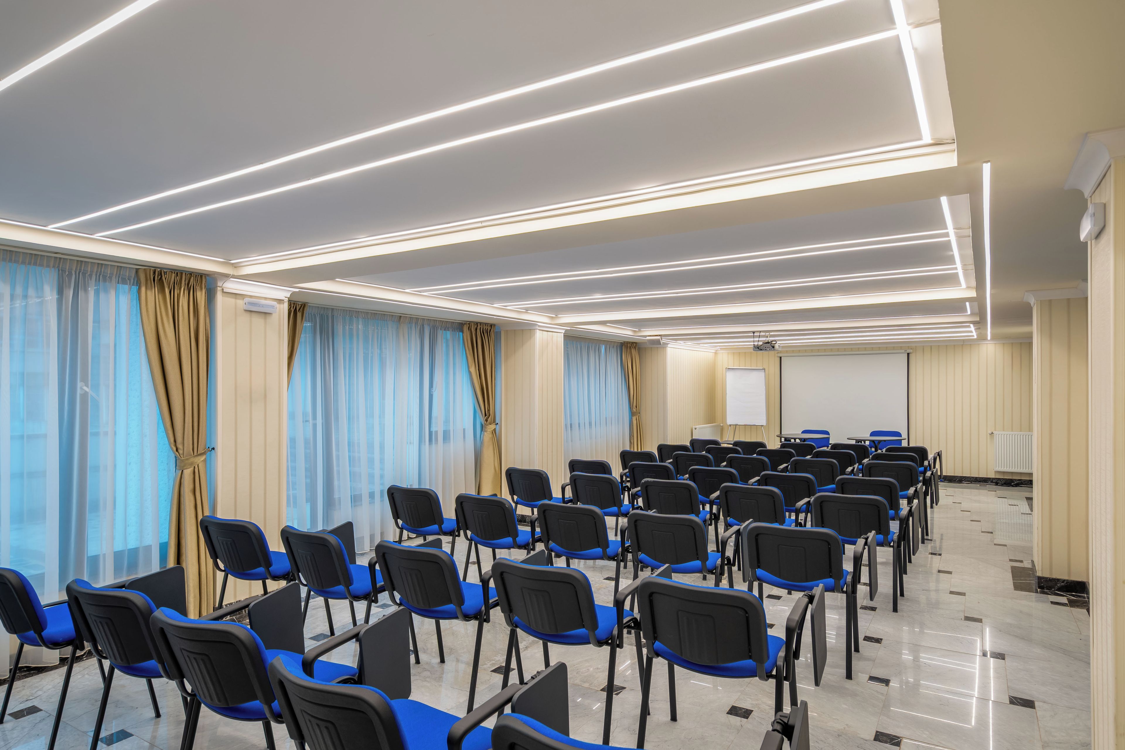 A conference room with rows of chairs, a projector screen, and a whiteboard.