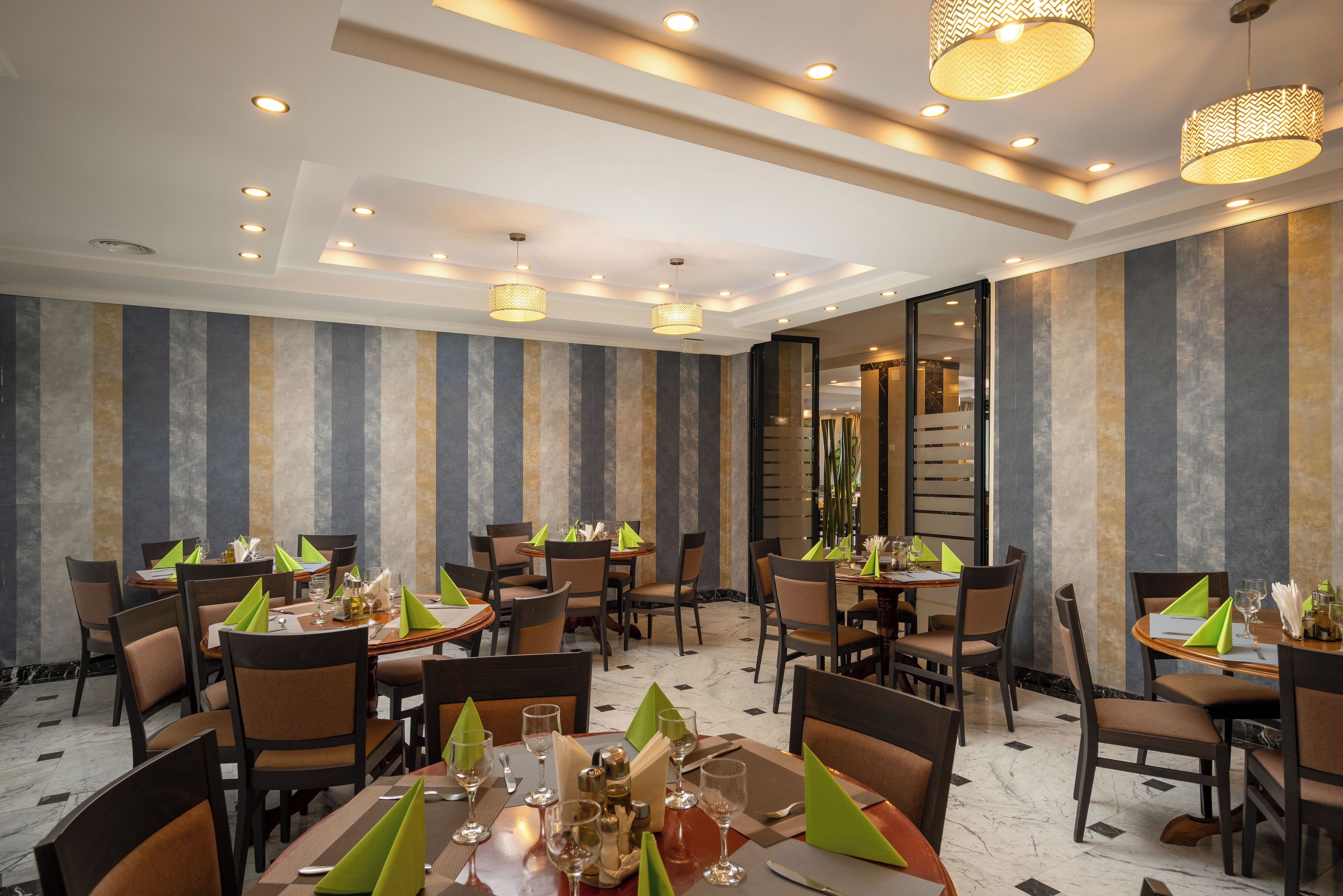 Een restaurant met meerdere tafels, stoelen en hanglampen.