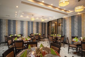 A restaurant with multiple tables, chairs, and hanging lamps. - Sarmis (Deva)