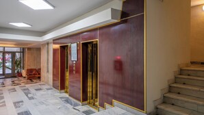 A lobby with a marble floor, a staircase, and a reception area with a desk and chairs. - Sarmis (Deva)